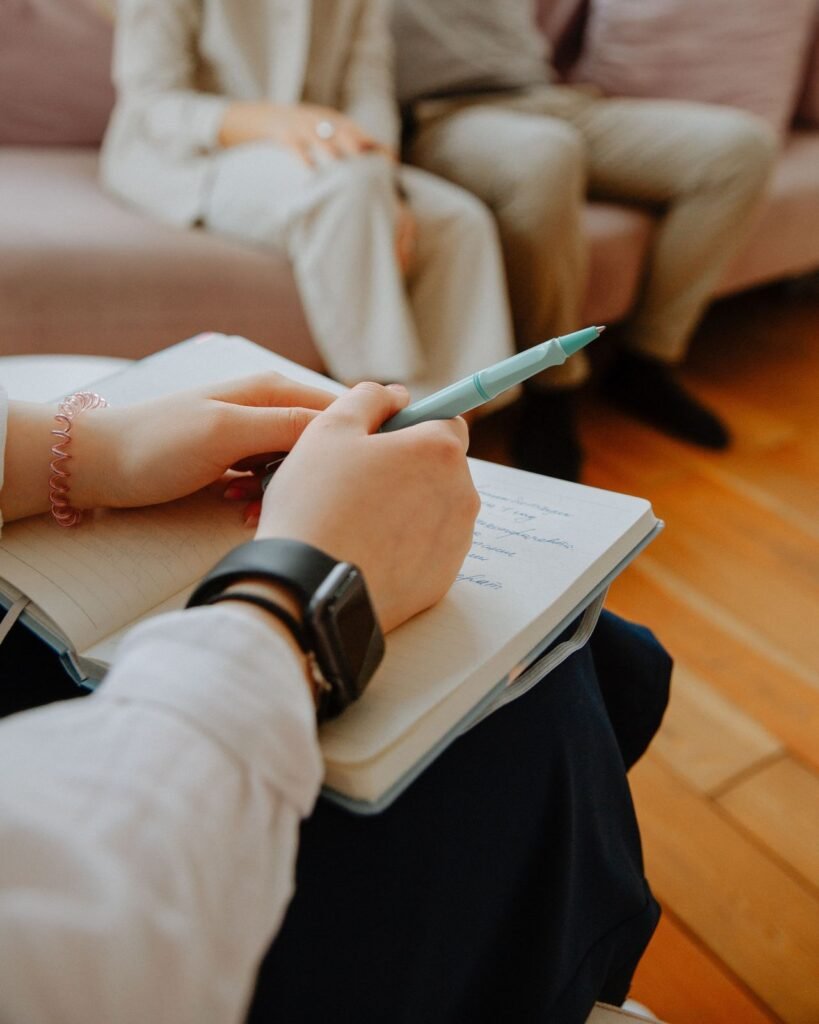 Clinician taking notes in a notebook during a counseling conversation