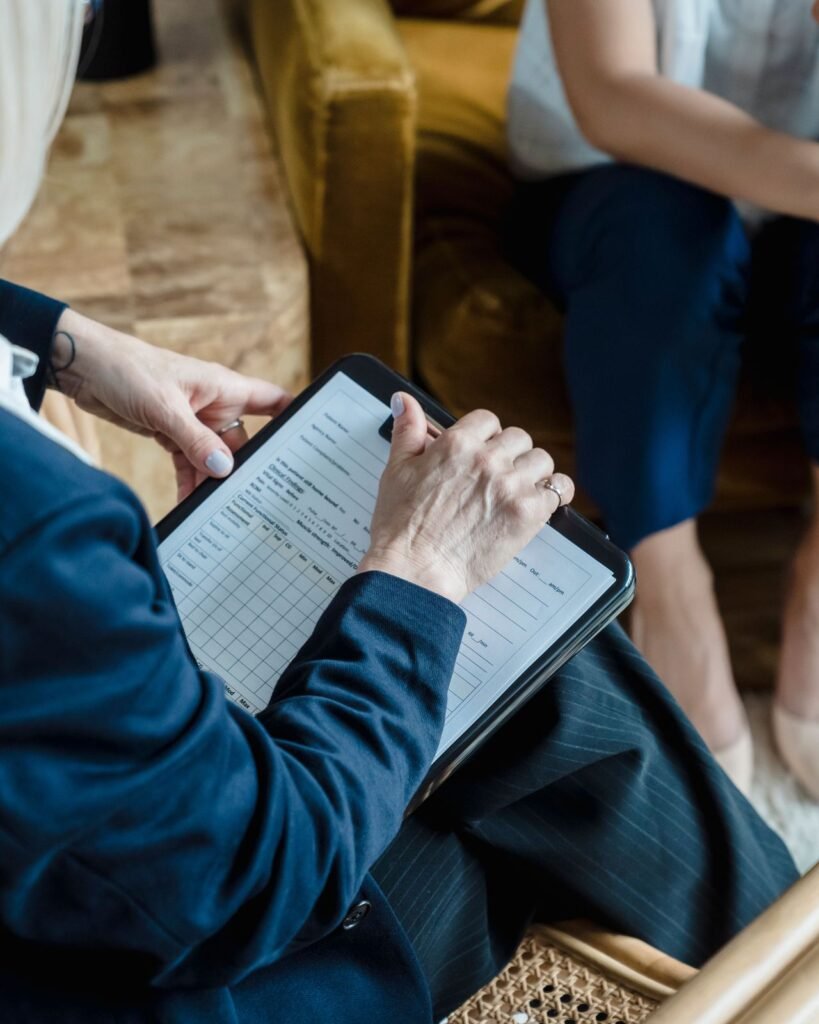 Clinician completing an intake form on a clipboard while a patient sits opposite